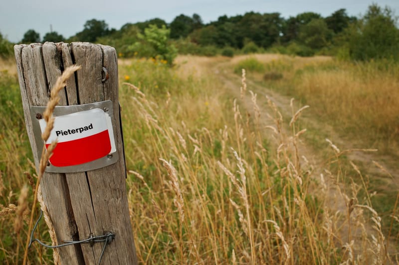 Pieterpad markering route op een paal met een veld erachter.
